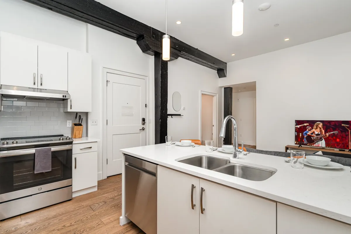 A stylish, open-concept kitchen and living area with a central island, stainless steel appliances, and visible space for entertaining. The setup is perfect for bringing takeout home, hosting group dinners, or lounging with friends between city adventures.